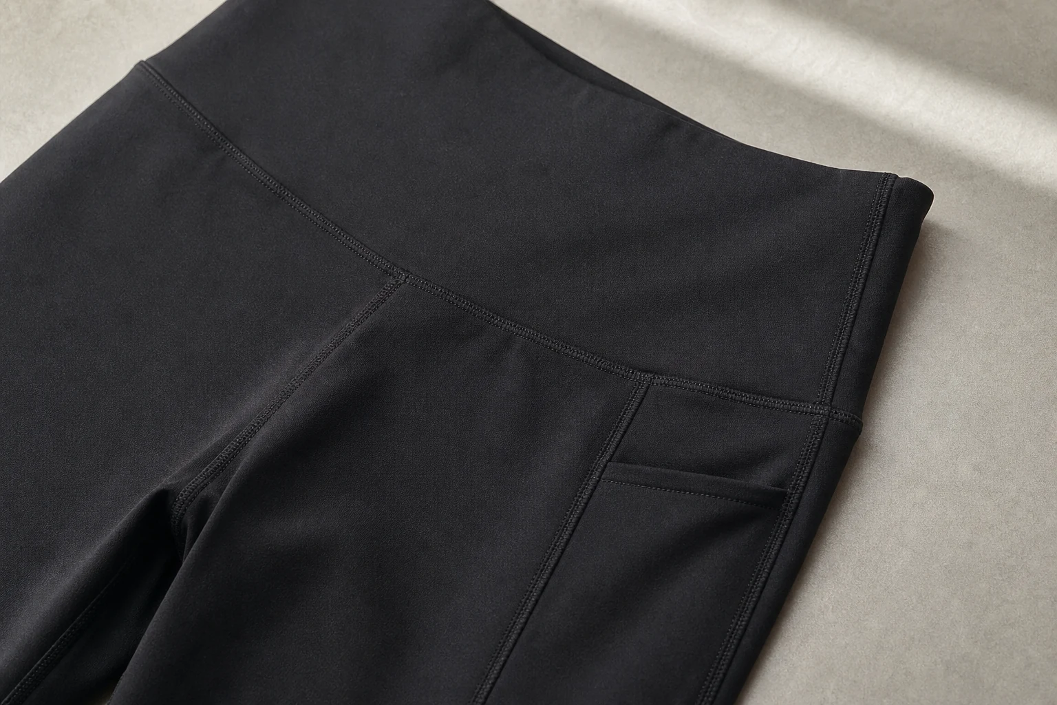 Black leggings waistband side pocket and seam construction detail for private-label activewear production.